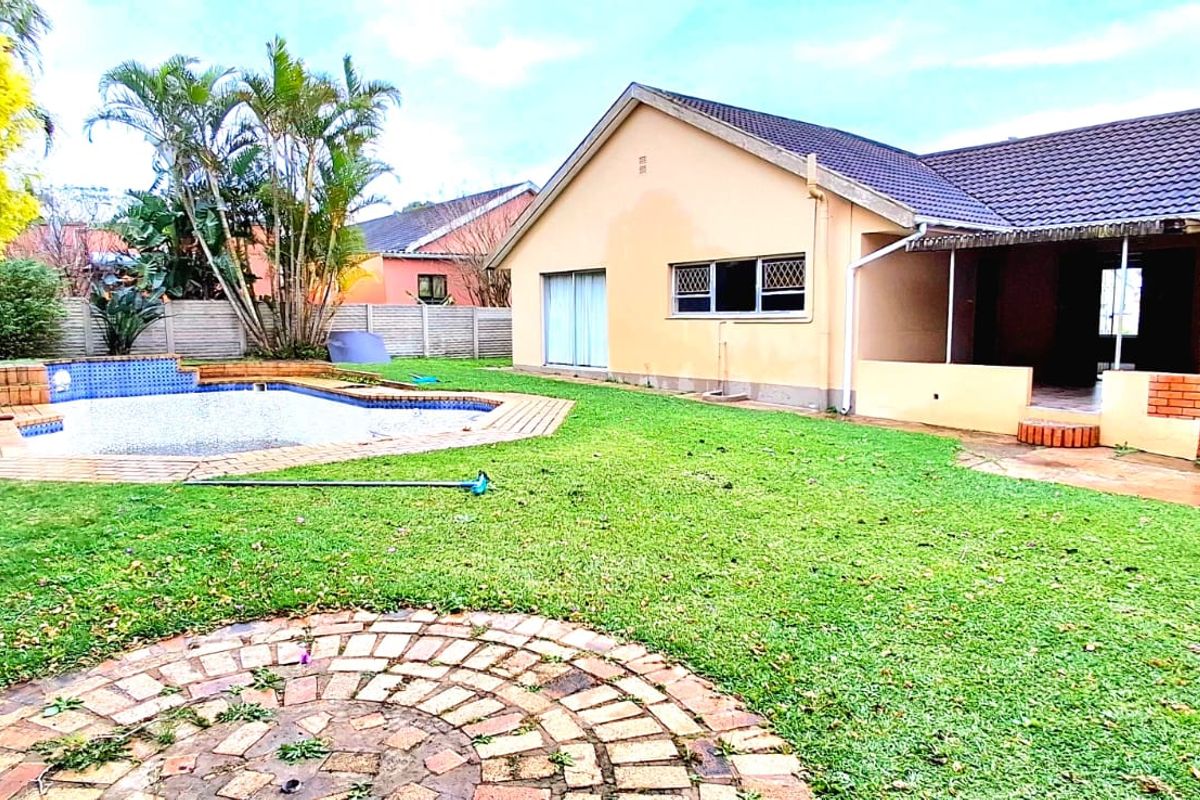 Rear view of the property featuring a swimming pool, brick chimney, and a paved patio area set within a private garden.