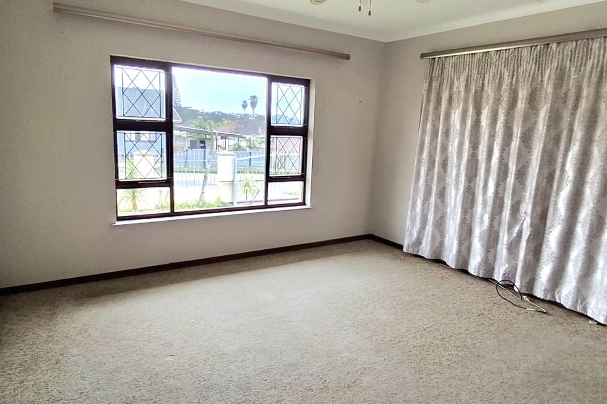 A vacant bedroom featuring carpeted flooring, leaded glass windows, and neutral wall finishes, offering a blank canvas for potential updates.