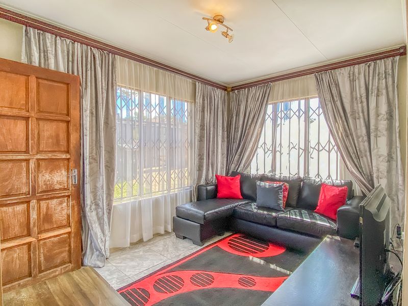 A living room featuring tiled flooring, security gates on windows, and a wooden door, offering a functional space with potential for modern updates.