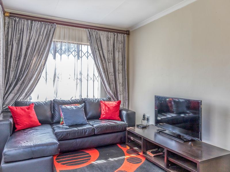 A cozy living room featuring a large window with a fitted security gate and curtain rod.