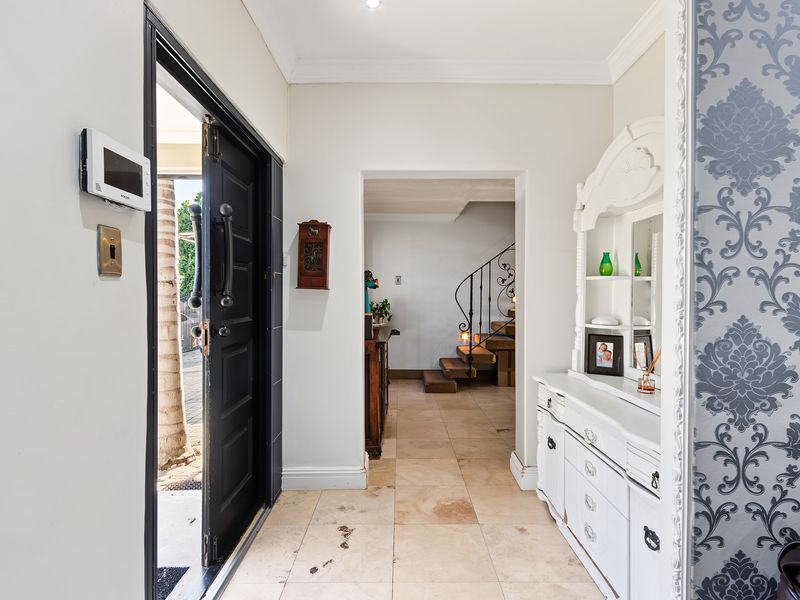 Welcoming entrance hall featuring tiled flooring, a security intercom system, and a view through to the staircase area.