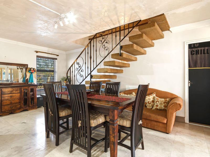 Dining area featuring tiled flooring, a distinctive wrought iron staircase railing, and a floating staircase design.