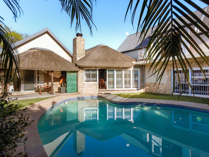 A well-maintained outdoor pool area featuring a swimming pool, stone-clad exterior walls, and traditional thatch roofing, providing a pleasant space for outdoor relaxation.