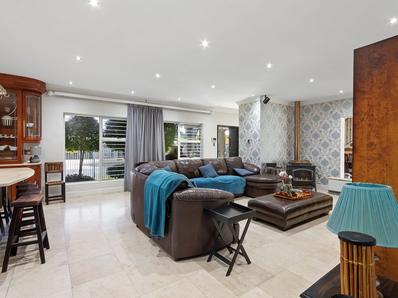 Spacious open-plan living area featuring tiled floors, recessed lighting, a built-in wood-burning fireplace, and a functional kitchen breakfast bar.