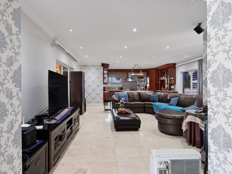 Spacious open-plan living area featuring tiled floors, recessed lighting, and a well-appointed kitchen with built-in cabinetry and integrated appliances.