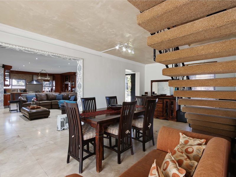 Open plan living and dining area featuring tiled flooring, a decorative ceiling, and a distinctive floating staircase with carpeted treads.