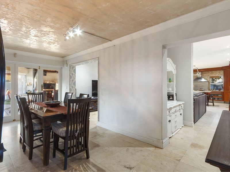 Open plan dining area featuring tiled flooring, coved ceilings, and direct access to the patio, with a view through to the kitchen area.