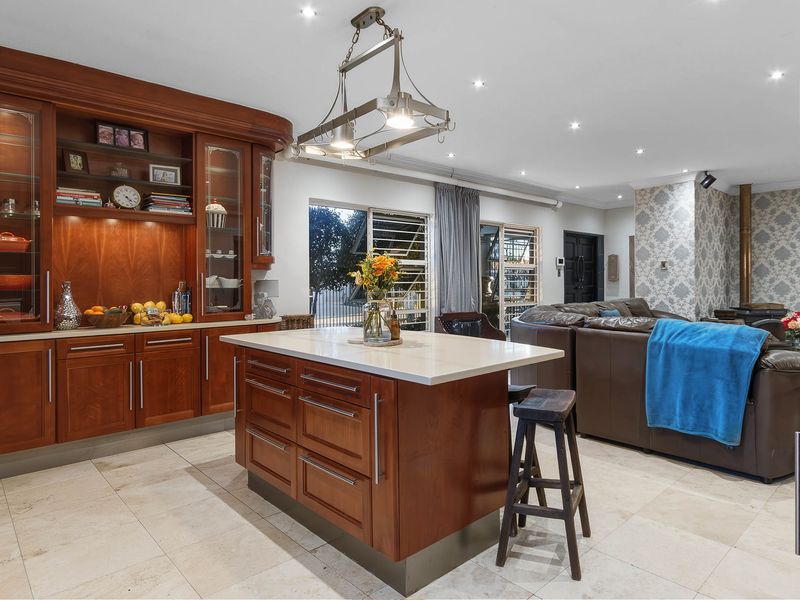 Spacious open-plan living area featuring a well-appointed kitchen with a central island, stone countertops, and warm wood cabinetry, seamlessly flowing into the lounge space.