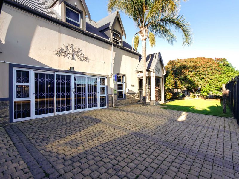 Front exterior view of the property featuring a paved driveway, security gates, and a multi-level facade with dormer windows.