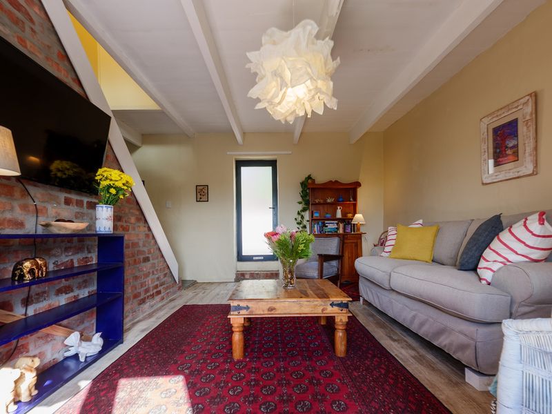 Cozy living room featuring an exposed brick feature wall, exposed timber ceiling beams, and direct access to the exterior via a glass panel door.