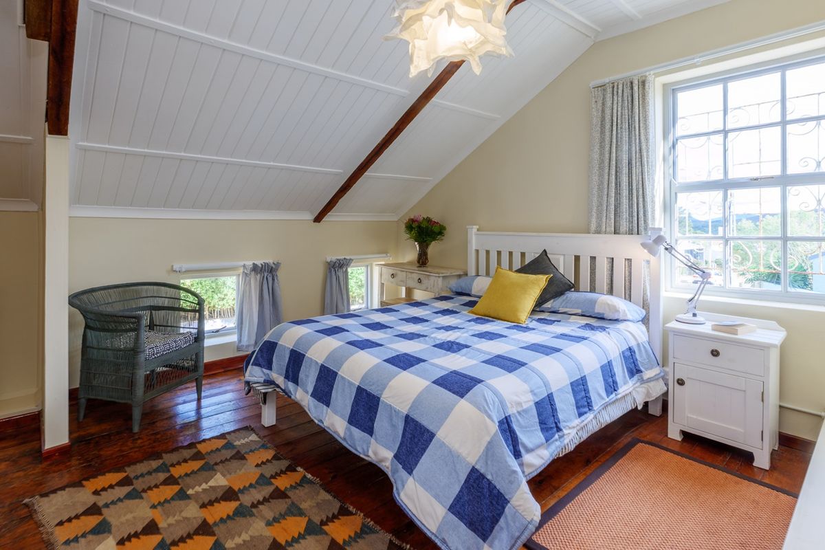 A cozy attic-style bedroom featuring warm timber flooring, exposed rafters, and a vaulted tongue and groove ceiling with natural light.