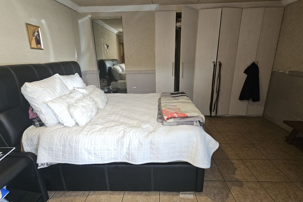 A bedroom featuring tiled flooring, crown molding, and extensive built-in cupboard storage with a mirrored section.