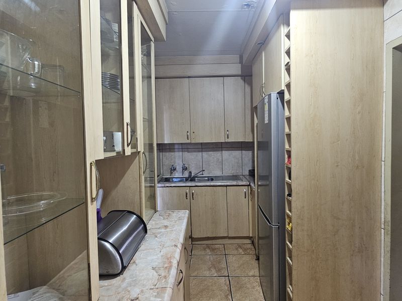 A functional scullery area featuring laminate cabinetry, a double bowl sink, tiled backsplash, and dedicated wine storage space.