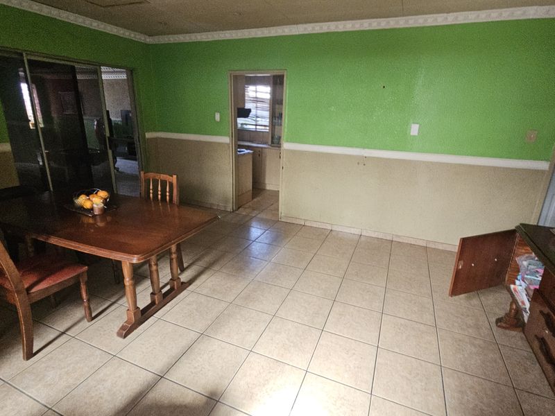 Dining room featuring ceramic floor tiles, decorative ceiling cornice, and access to an adjacent kitchen area through a central doorway.