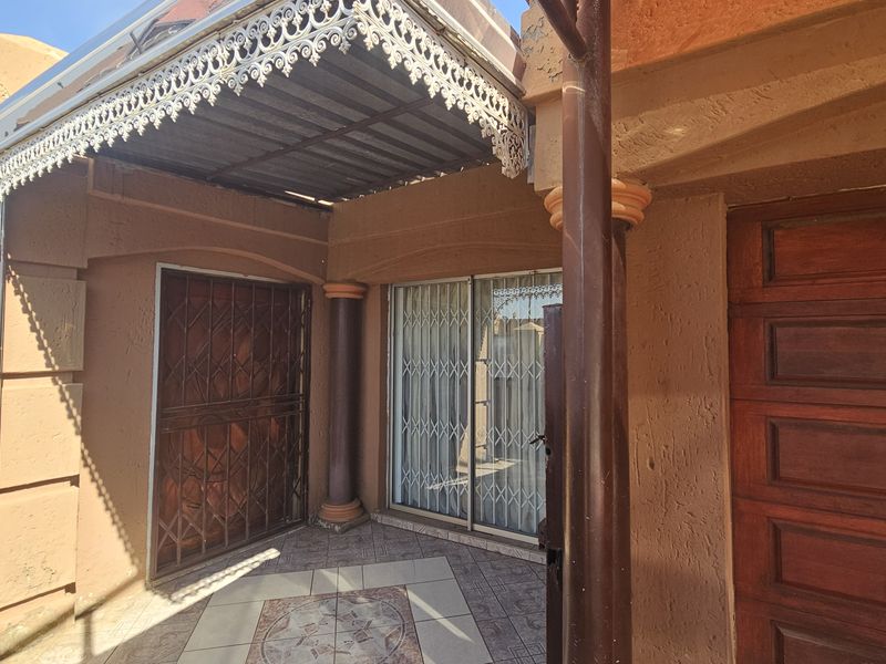 Covered patio area featuring decorative iron trim, tiled flooring, and secure access points with security gates and sliding doors.
