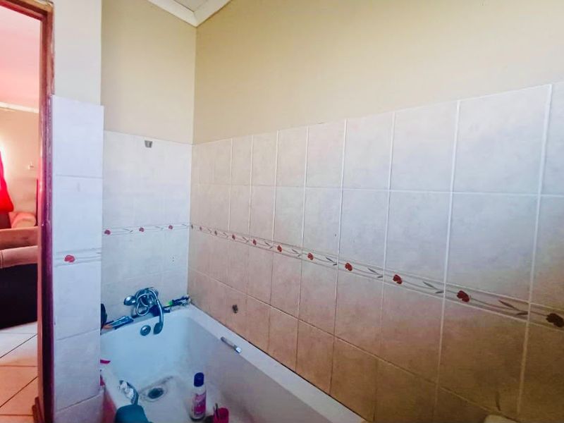 A functional bathroom featuring a built-in bathtub with wall tiling, requiring some cosmetic updates to improve the overall aesthetic and finish.