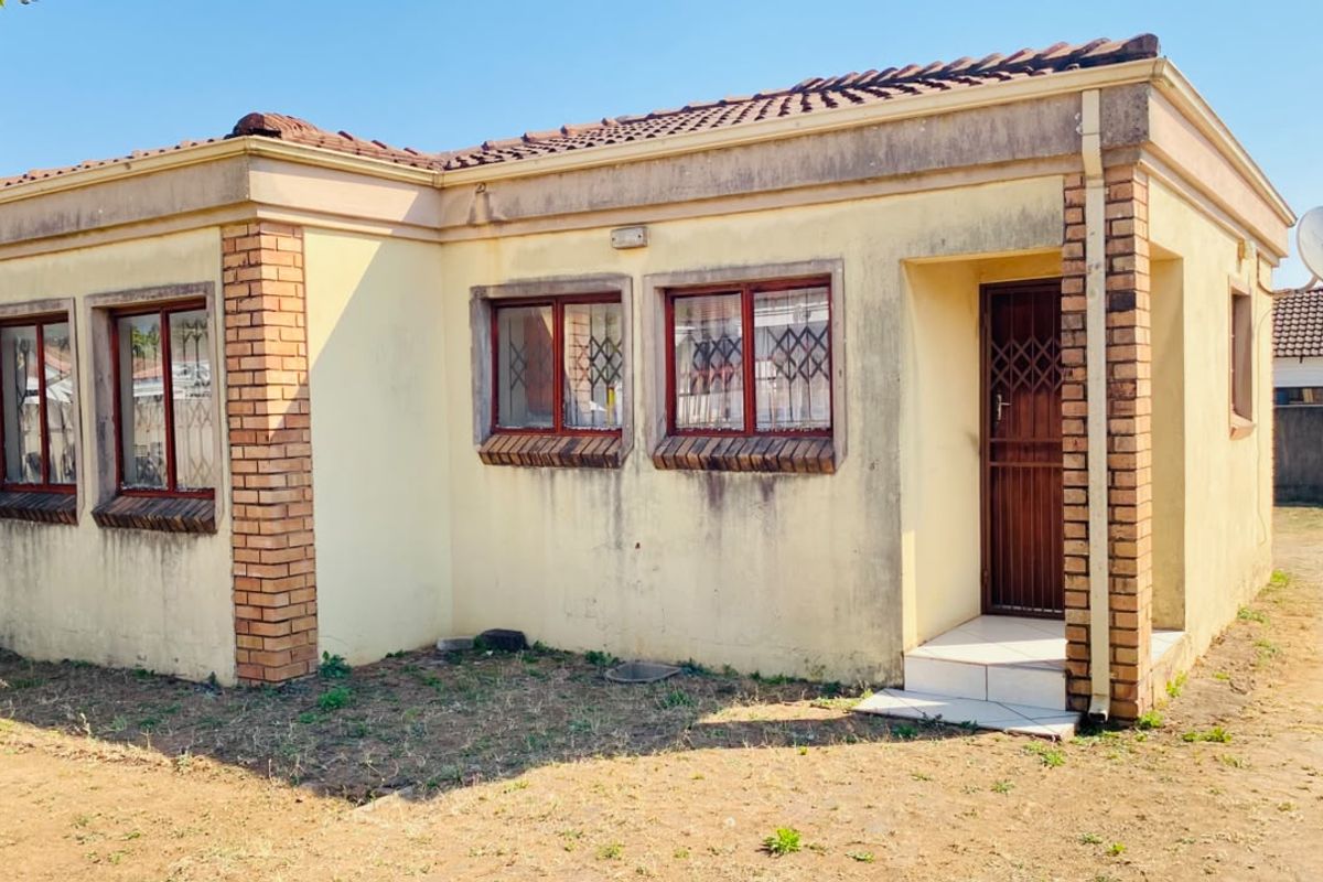 Single-story residential house featuring a brick and plaster facade, tiled roof, and security gates at the entrance.