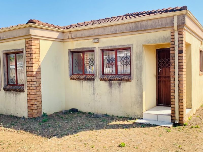 Single-story residential house featuring a brick and plaster facade, tiled roof, and security gates at the entrance.