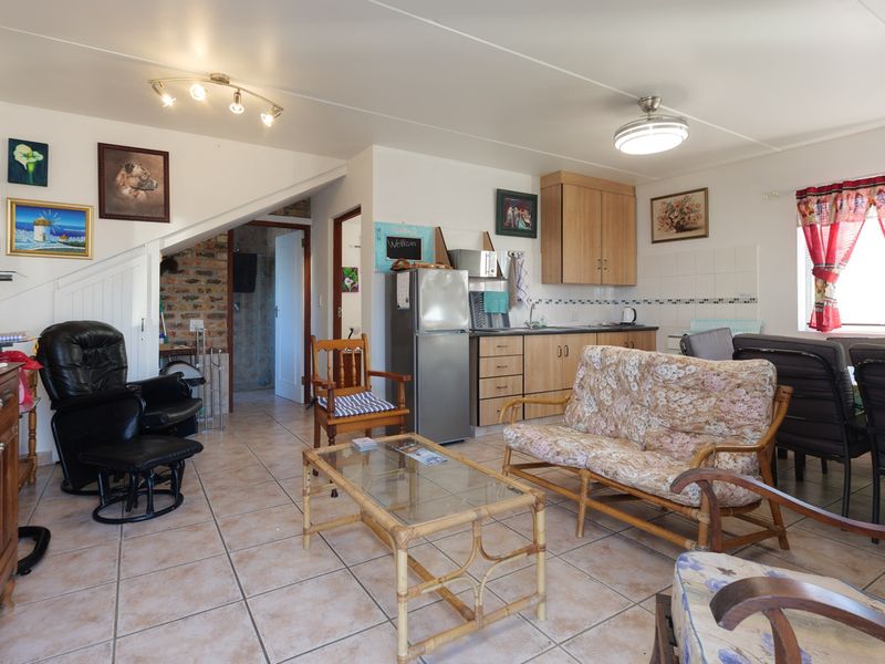Open-plan living and kitchen area featuring tiled flooring, built-in cabinetry, and an exposed brick feature wall, offering a functional and versatile living space.