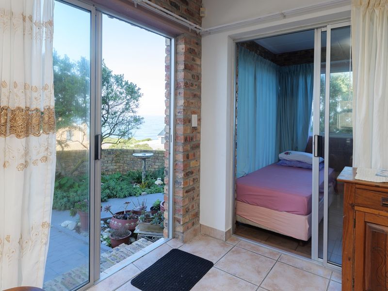 Enclosed patio area featuring exposed brick walls and sliding glass doors providing access to the garden and ocean views.