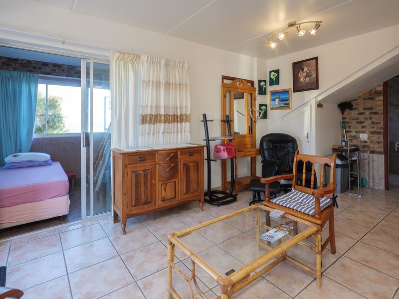 Living area featuring tiled flooring, exposed brick accents, and a sliding glass door providing access to an adjacent bedroom or balcony space.