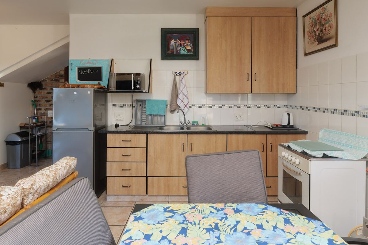 A functional kitchen featuring laminate cabinetry, a double bowl sink, tiled splashback, and a freestanding oven, with tiled flooring throughout.