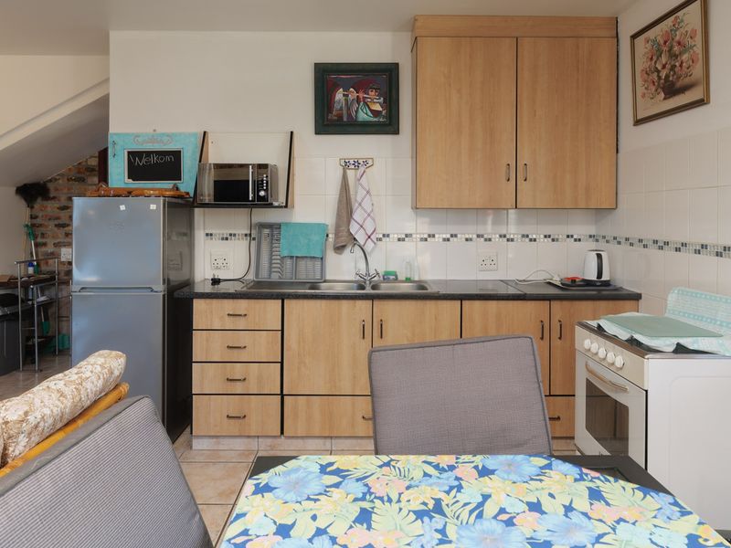 A functional kitchen featuring laminate cabinetry, a double bowl sink, tiled splashback, and a freestanding oven, with tiled flooring throughout.