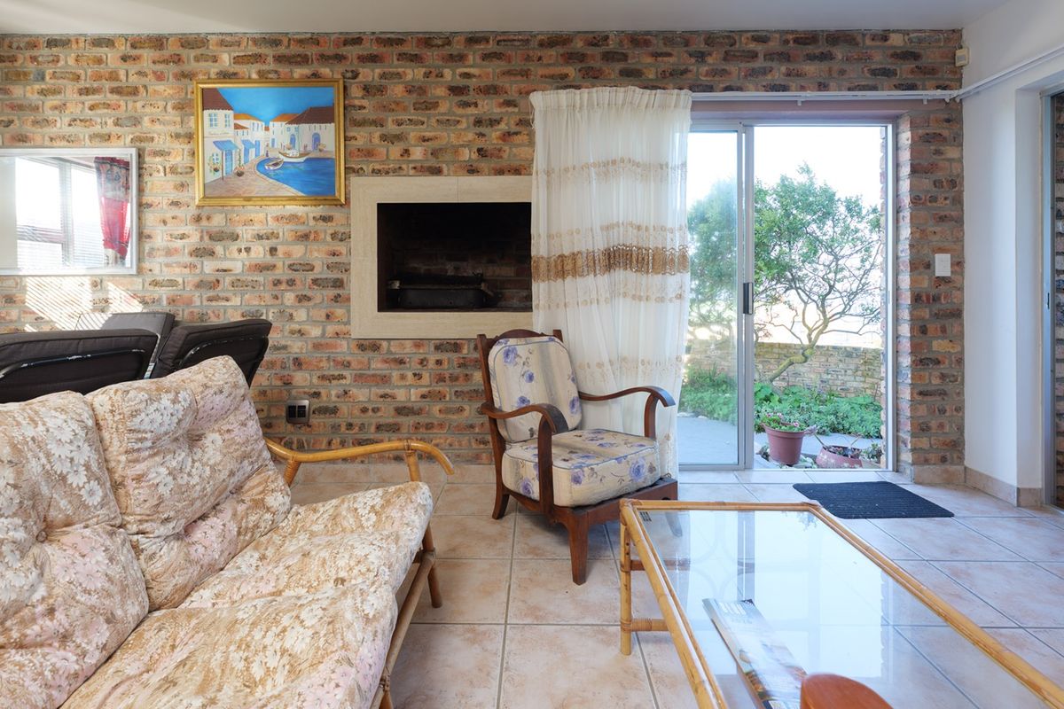 Living room featuring an exposed brick wall, a built-in fireplace, and sliding glass doors providing access to the outdoor area.