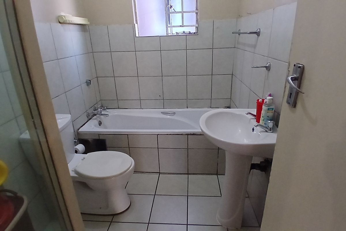 A functional bathroom featuring a bathtub, pedestal basin, toilet, and a separate shower enclosure with tiled finishes throughout.