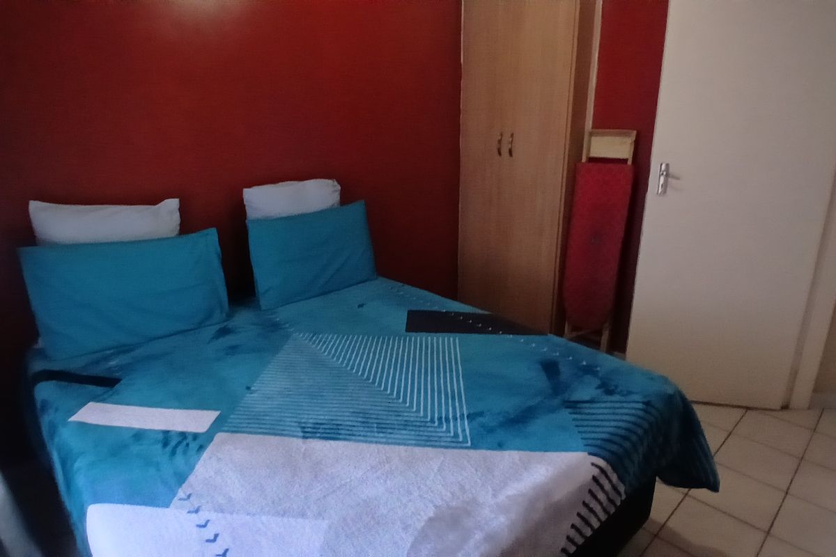 A bedroom featuring tiled flooring and a built-in wardrobe, currently finished with bold red wall paint.