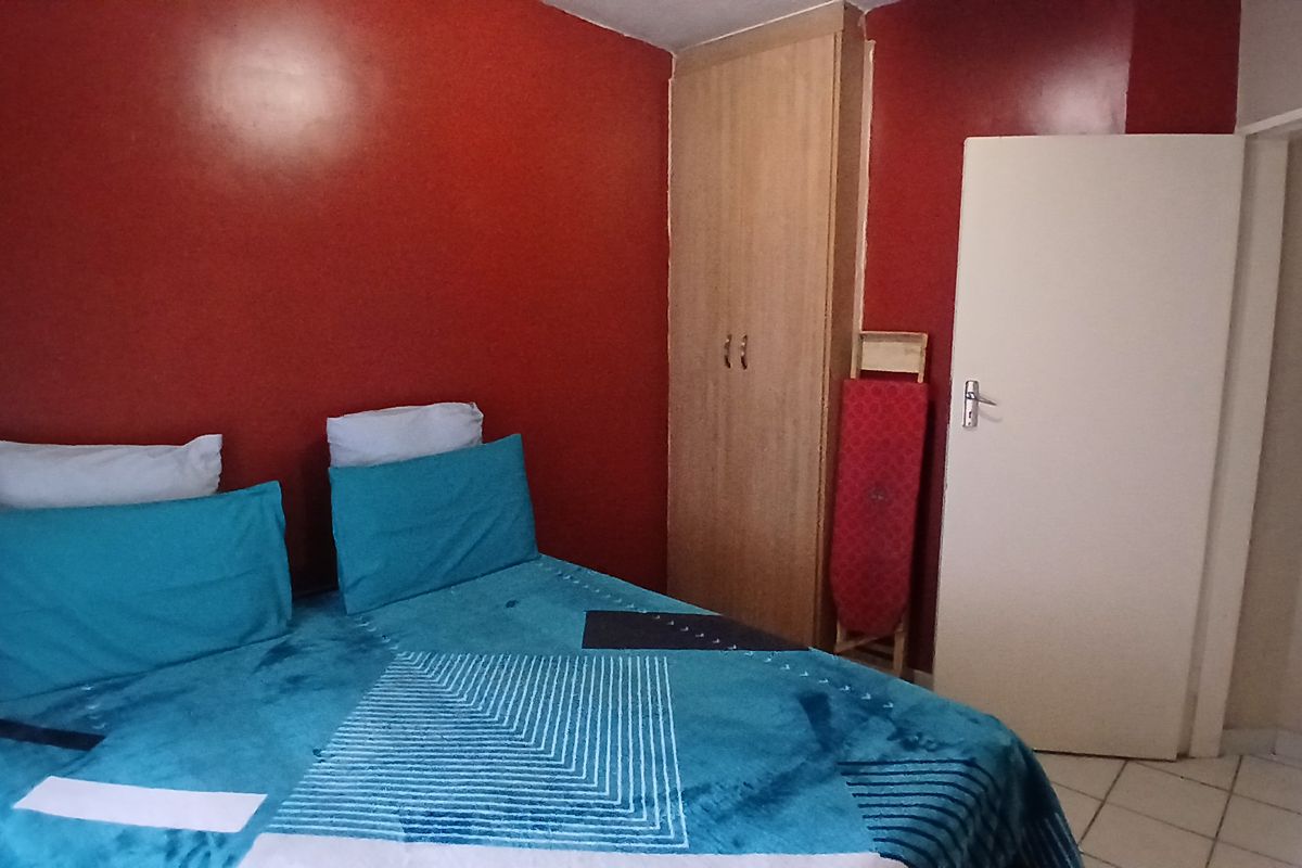 A bedroom featuring a built-in wardrobe and tiled flooring, finished with bold red wall paint.