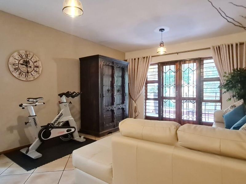 A living room featuring tiled flooring and sliding glass doors with security gates, providing access to the outdoor area.