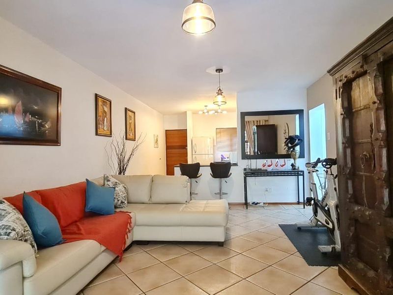 Open-plan living area featuring ceramic floor tiles, a breakfast bar, and integrated kitchen space, offering a functional layout for modern apartment living.