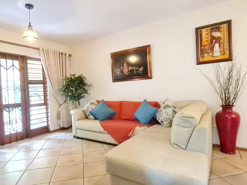 A bright living room featuring tiled flooring and a timber-framed glass door with an integrated security gate, providing access to the exterior.
