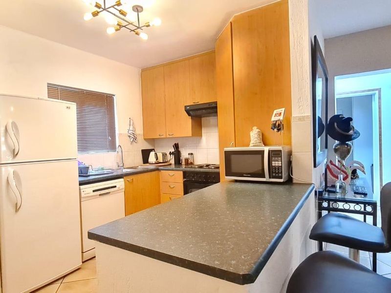 A functional kitchen featuring laminate cabinetry, a breakfast bar, and integrated appliances, offering a practical layout for daily cooking and dining.