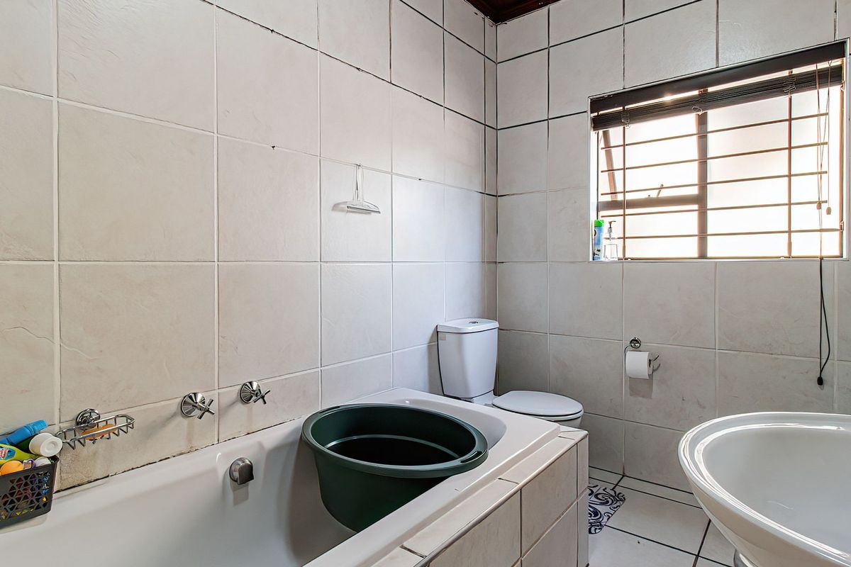 A functional bathroom featuring a bathtub, toilet, and tiled surfaces. The space would benefit from cosmetic updates to modernize the finishes.