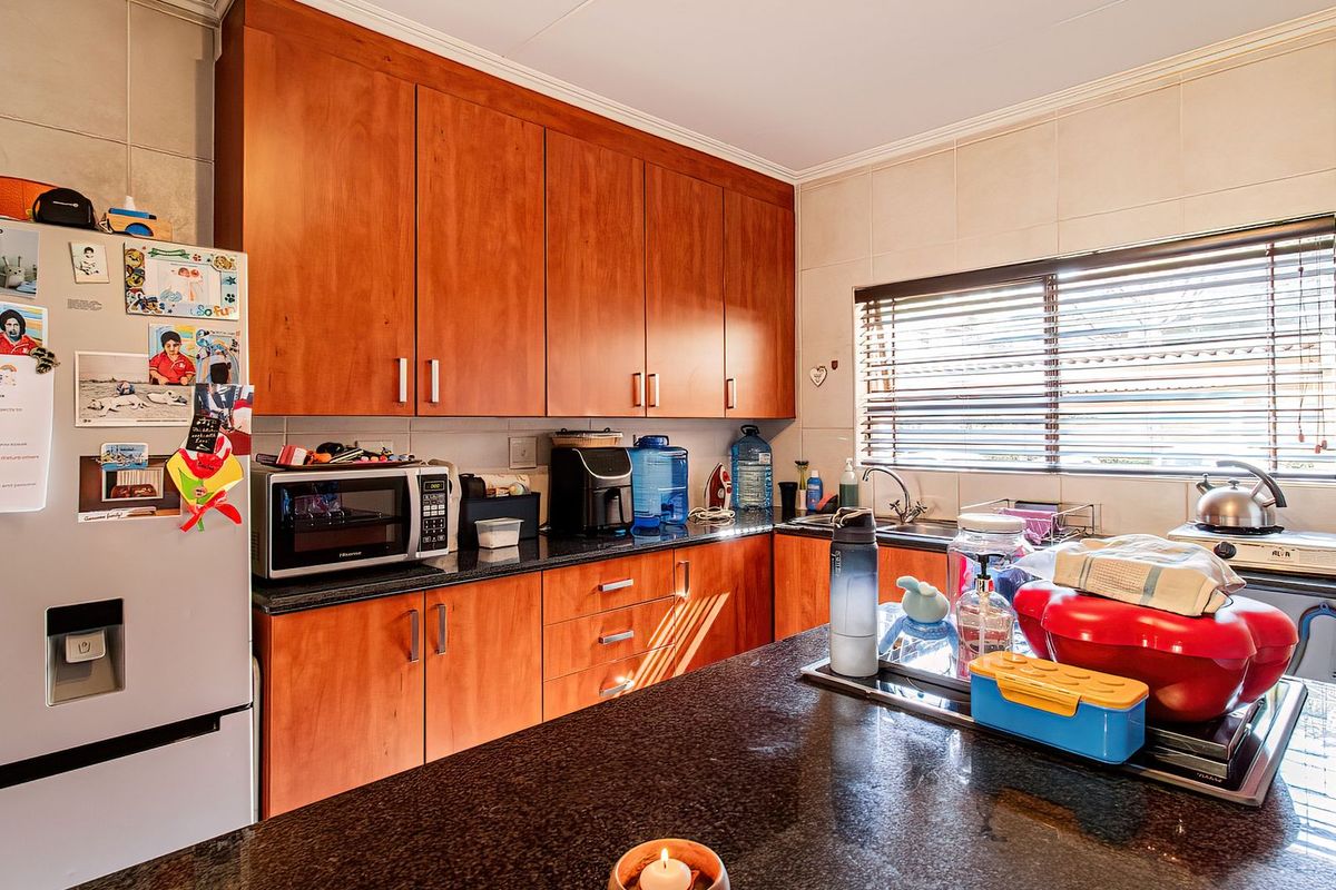 A functional kitchen featuring warm-toned wooden cabinetry, dark granite countertops, and a tiled backsplash, providing ample storage and workspace.