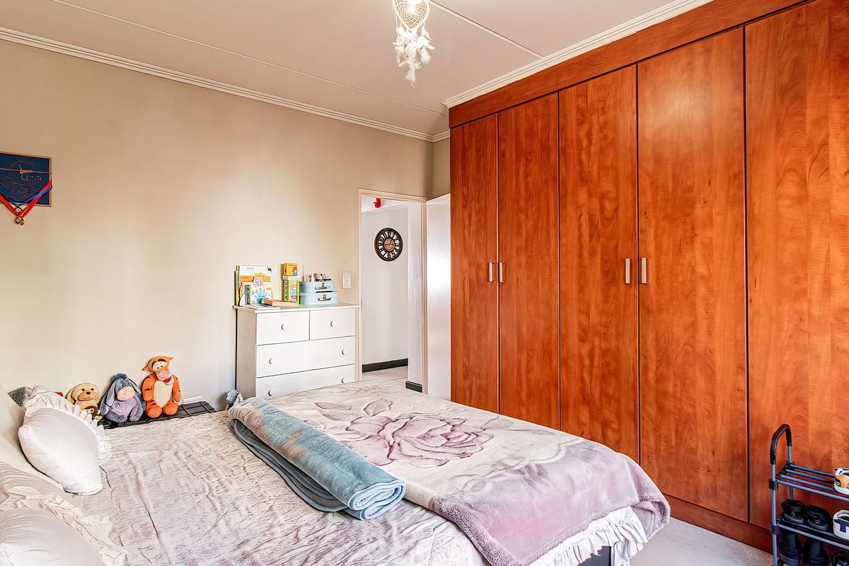 A bedroom featuring extensive floor-to-ceiling built-in wooden wardrobes, coving, and neutral wall finishes.