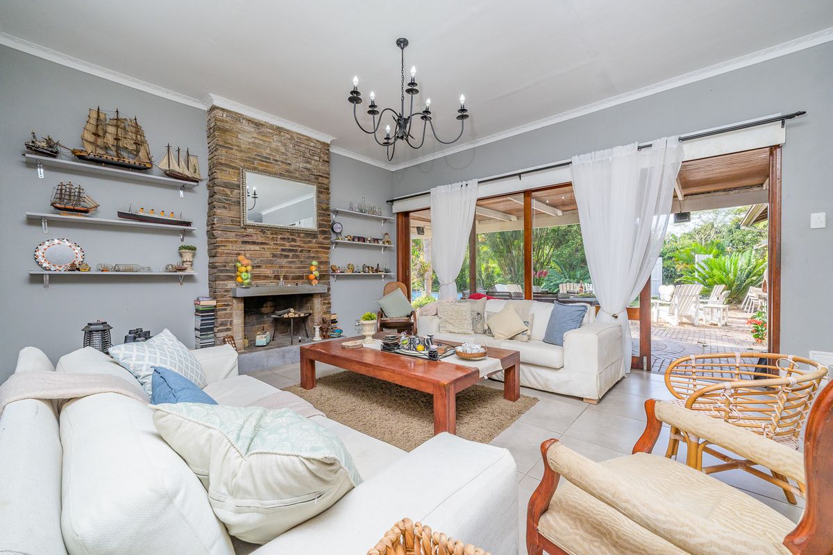 Spacious living room featuring a prominent stone fireplace, tiled flooring, and large sliding glass doors providing seamless access to the outdoor patio area.