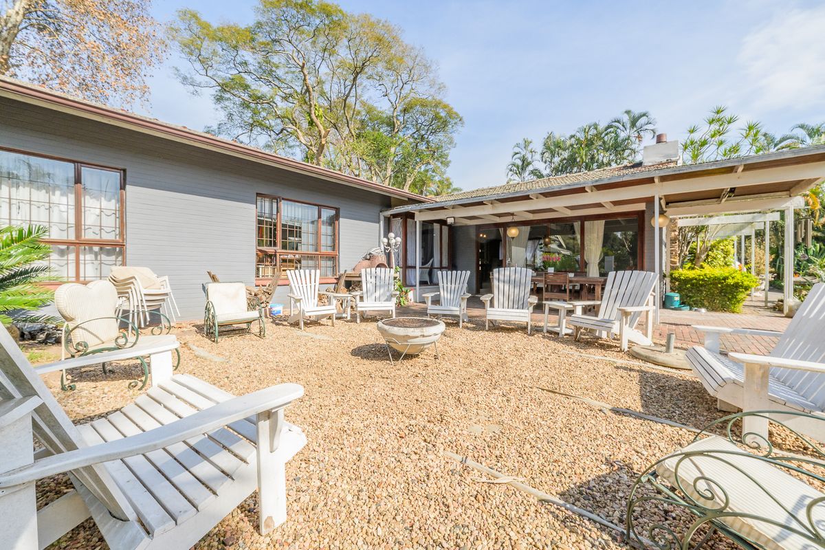 Rear exterior view featuring a gravel courtyard, brick paved areas, and a covered patio space attached to the main dwelling.