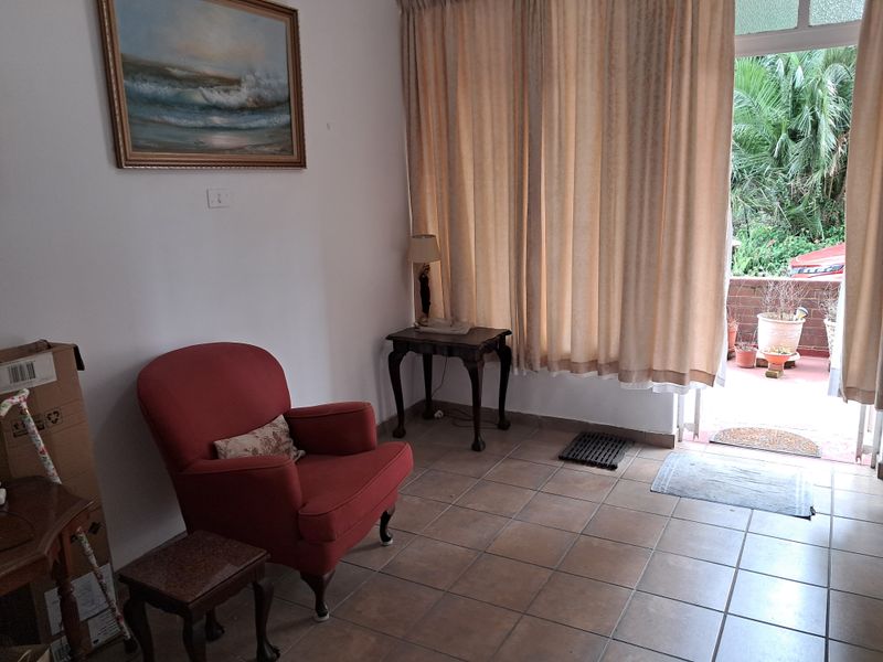 A living area featuring tiled flooring and direct access to an outdoor patio space through a sliding glass door.