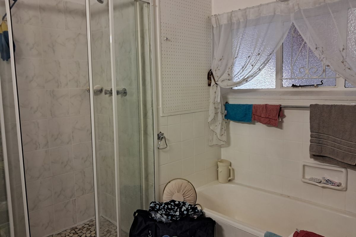 Bathroom featuring a separate shower enclosure with pebble flooring, a built-in bathtub, and tiled wall finishes.