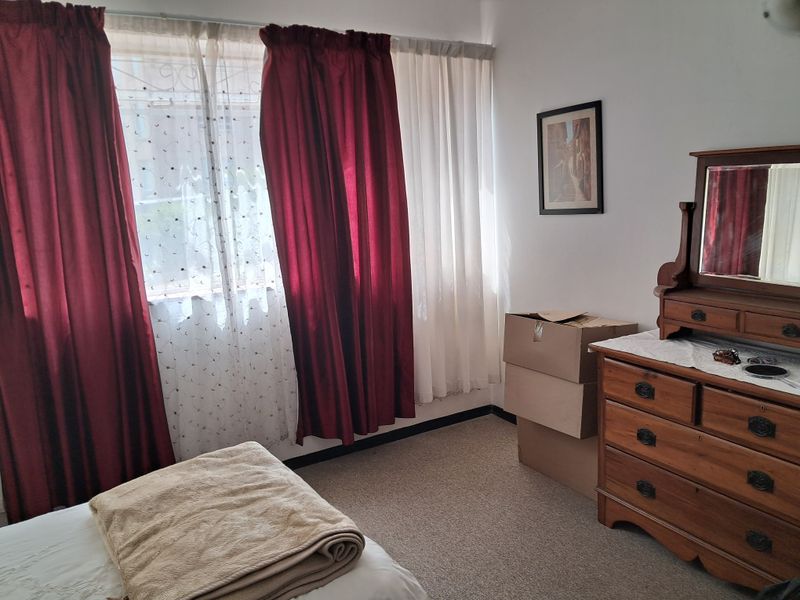 A standard bedroom featuring carpeted flooring and window security bars, offering a functional space with natural light.