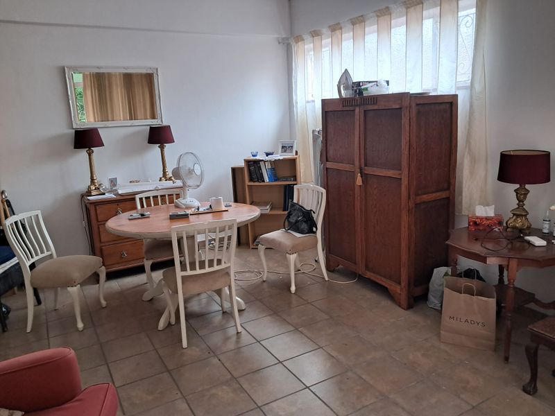 A living area featuring tiled flooring and large windows with curtain rails, offering a functional space ready for modernization.