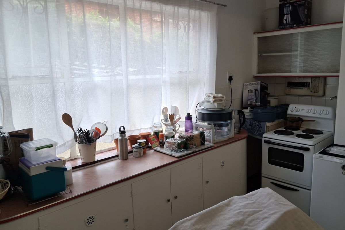 A functional kitchen featuring laminate countertops, built-in cabinetry, and a freestanding electric stove, offering potential for modernization and improved layout efficiency.