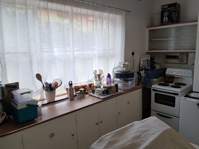 A functional kitchen featuring laminate countertops, built-in cabinetry, and a freestanding electric stove, offering potential for modernization and improved layout efficiency.