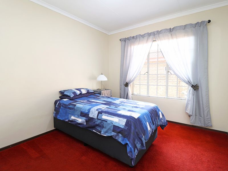 A standard bedroom featuring carpeted flooring and a window with curtain treatments.