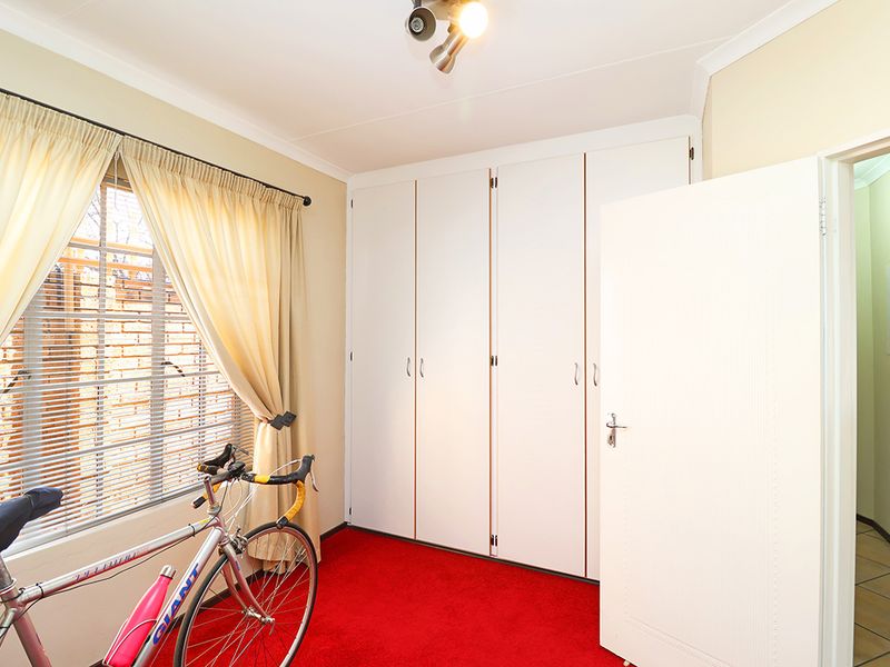 A bedroom featuring built-in cupboards, carpeted flooring, and a ceiling-mounted spotlight, offering functional storage and a neutral layout.
