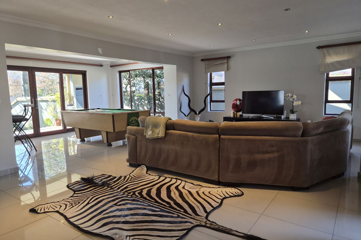 Spacious open-plan living area featuring polished porcelain floor tiles, recessed downlighting, and large sliding glass doors providing ample natural light and garden access.