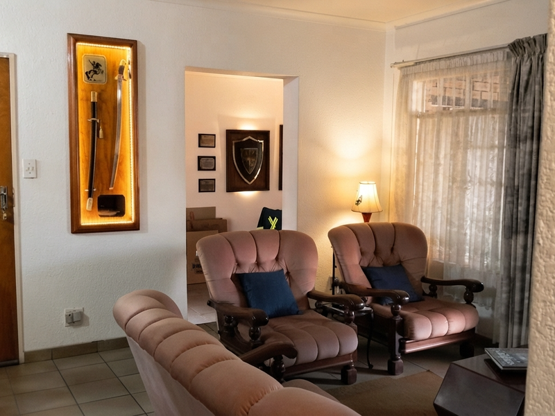 A living room area featuring tiled flooring, a wooden entrance door, and natural light through window curtains.